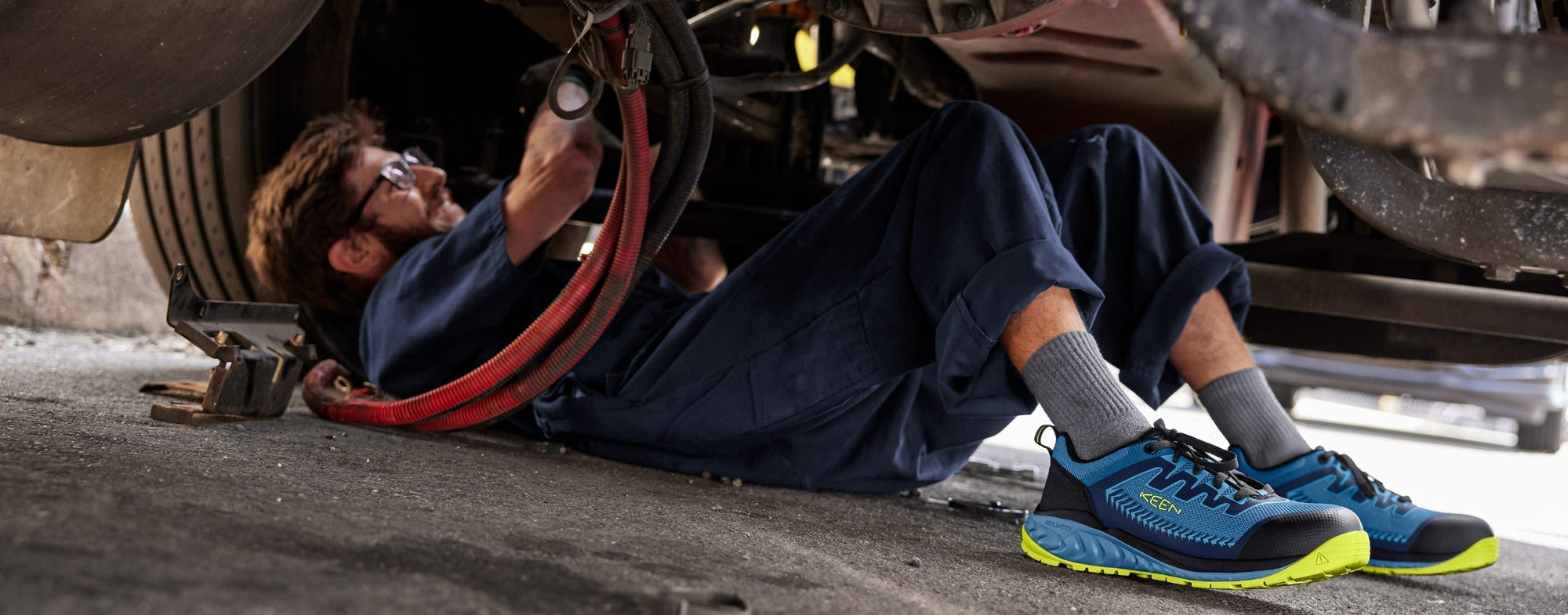 mechanic working under vehicle wearing KEEN shoes
