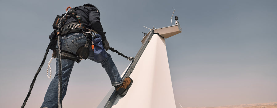 Worker standing on wind turbine above wheatfields