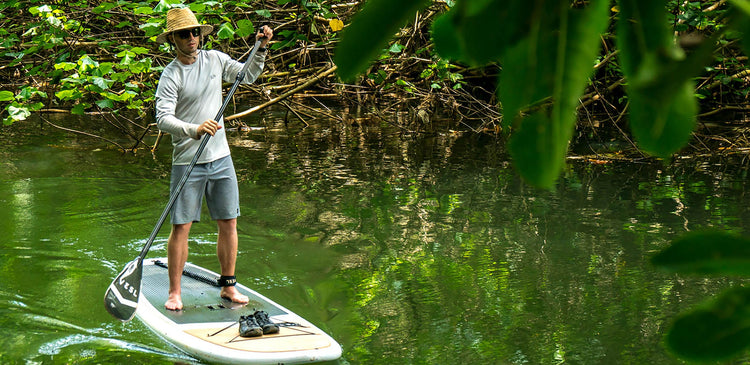 A man stand-up paddleboarding on a river in Hawaii