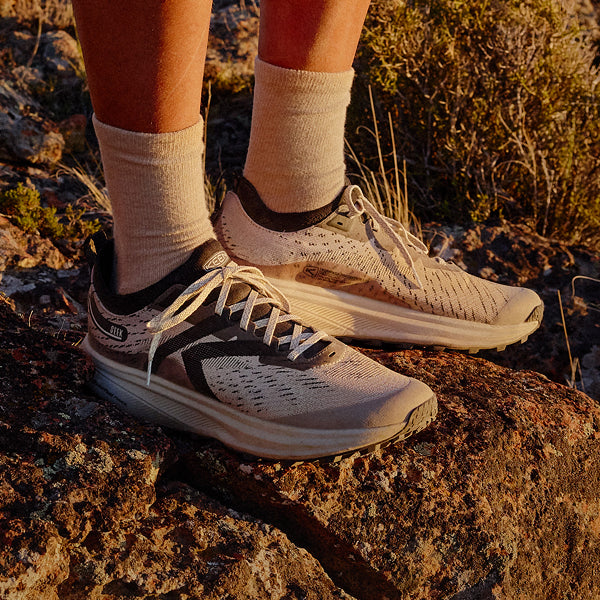 Knee-down shot of person wearing Seek running shoes with gray crew socks 