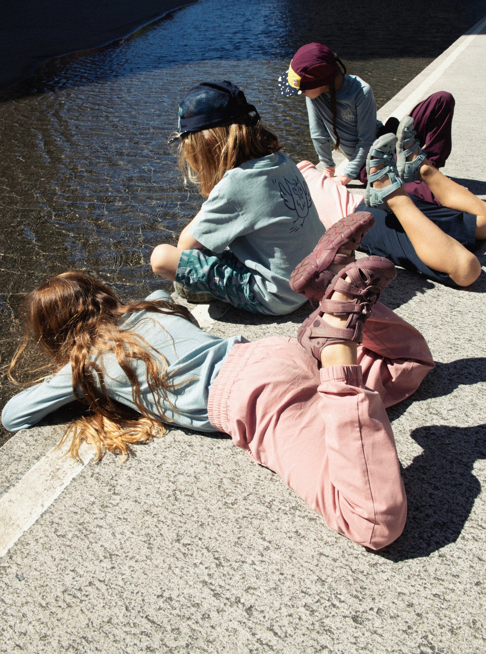 Four kids looking into city pond while wearing namuk collaboration seacamp II CNX sandals in monochrome colors.