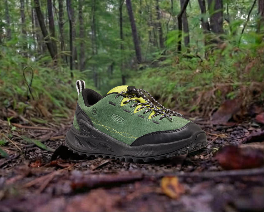 The new Kid's Jasper Zionic sneaker resting on rocky terrain in a green forest.