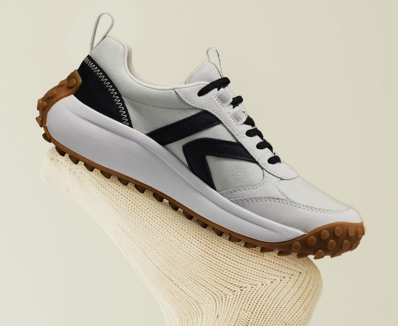  A black and white KS86 sneaker resting on a knitted sock, showcasing its stylish design and casual appeal.