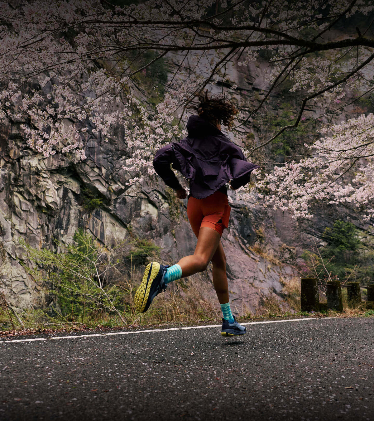 Woman running up paved road in Roam Leather running shoes