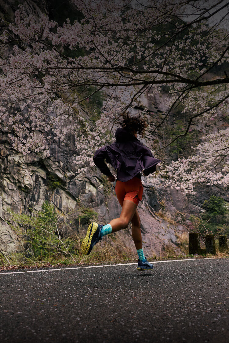 Woman running up paved road in Roam Leather running shoes