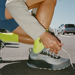Person kneeling in parking lot tying shoe lace on Seek running shoe