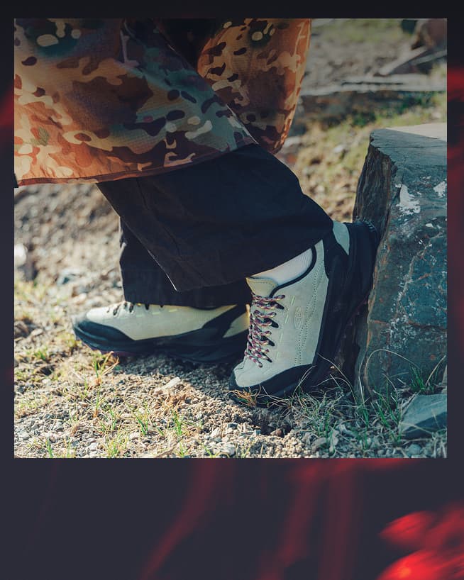 Close up shot of woman wearing a camo skirt over black pants and teal, pink, and black Jasper zionic sneakers.