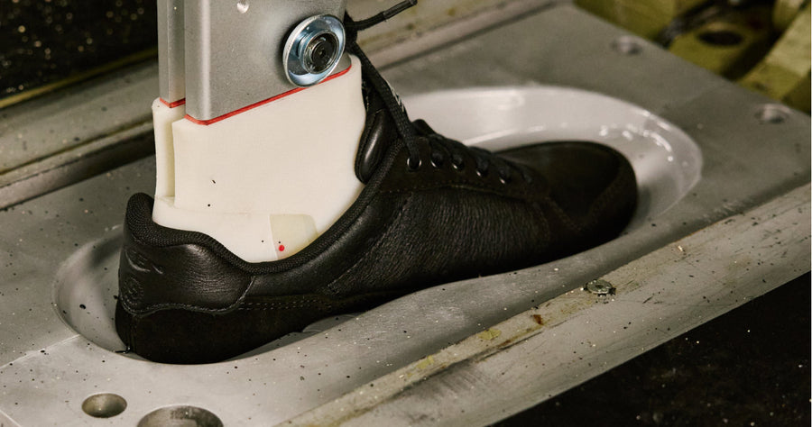 A machine holding the upper part of a shoe, in motion, showing the attachment of the sole using KEEN Fusion technology.