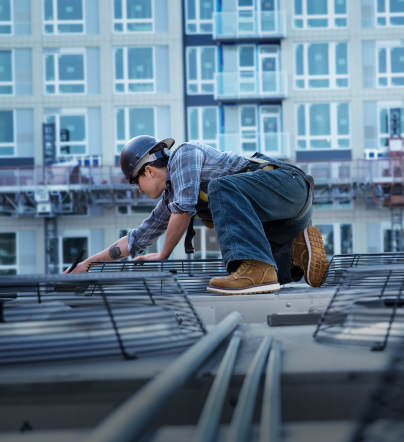 A woman working on a job site, wearing a pair of KEEN work boots.
